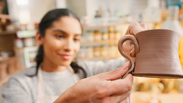 istock Female Potter Fitting Clay Handles To Mugs In Ceramics Studio 2247301621