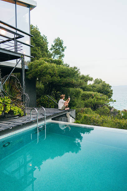 istock Man sitting on the edge of the infinity pool 2247303352