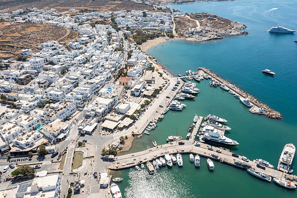Aerial photograph of Naousa, Paros, Greece, capturing the busy marina, seaside promenade, and hillside village.