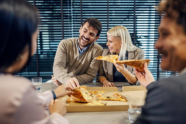 istock Coworkers enjoying lunch break laughing and eating pizza 2247304191