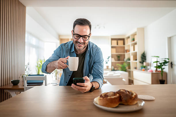 istock Smiling man having coffee breakfast and looking at phone 2247308953