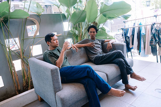 istock Young Men Relaxing with Drinks on Sofa in Casual Setting 2247309602