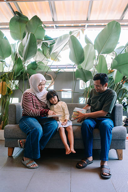 istock Family Bonding: Parents Reading Stories with Daughter in Green Setting 2247310057