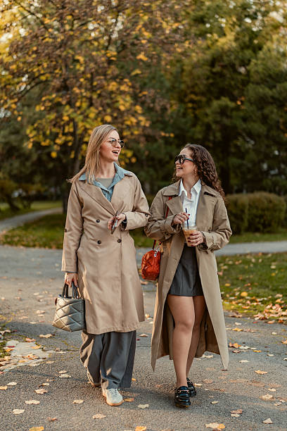 istock Female modern friends having pleasant conversation while walking together in the public park on sunny autumn day. 2247314283