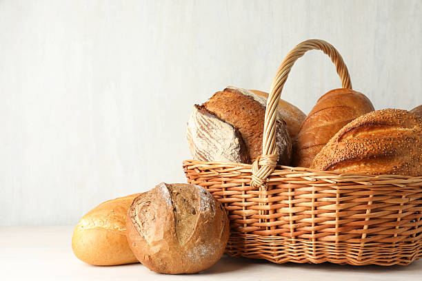 istock Different freshly baked bread loafs and wicker basket on white wooden table, closeup. Space for text 2247314793