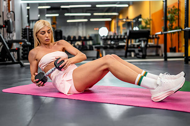 istock Woman doing russian twist exercise with dumbbell in gym 2247317245