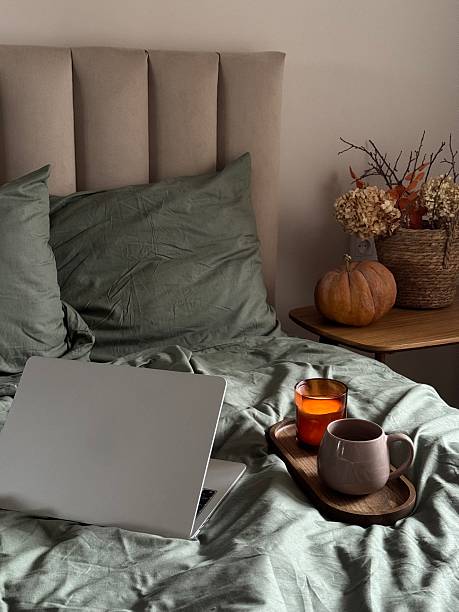 autumn home decoration.charming breakfast and work cozy nook, burning candle,intimate and serene workspace with notebook and warm breakfast ambiance on bed.