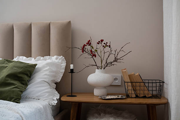 istock Cozy fall decor in a light and bright bedroom, bed, white bed sheets, autumn branches in white vase, candle and books on wooden bench. 2247319814