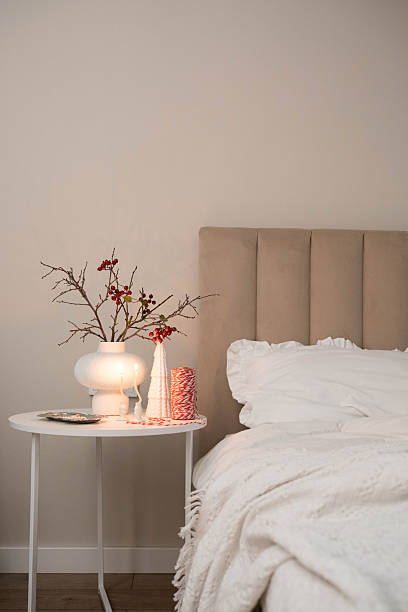 istock Cozy Christmas decor in a light and bright bedroom, bed, white bed sheets, fir branches in a white vase, candles on white table 2247320031