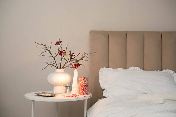 istock Cozy Christmas decor in a light and bright bedroom, bed, white bed sheets, fir branches in a white vase, candles on white table 2247320169