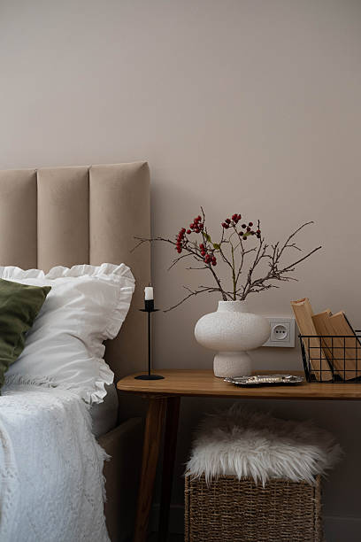 istock Cozy fall decor in a light and bright bedroom, bed, white bed sheets, autumn branches in white vase, candle and books on wooden bench. 2247320519