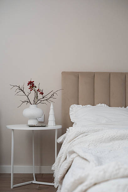 istock Cozy Christmas decor in a light and bright bedroom, bed, white bed sheets, fir branches in a white vase, candles on white table 2247320686