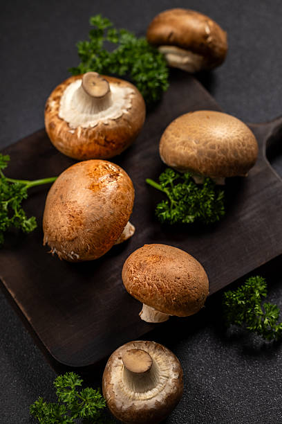 istock Fresh brown cremini mushrooms and parsley on dark board 2247320751