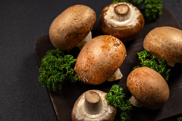 istock Fresh cremini mushrooms and parsley on dark board 2247321321