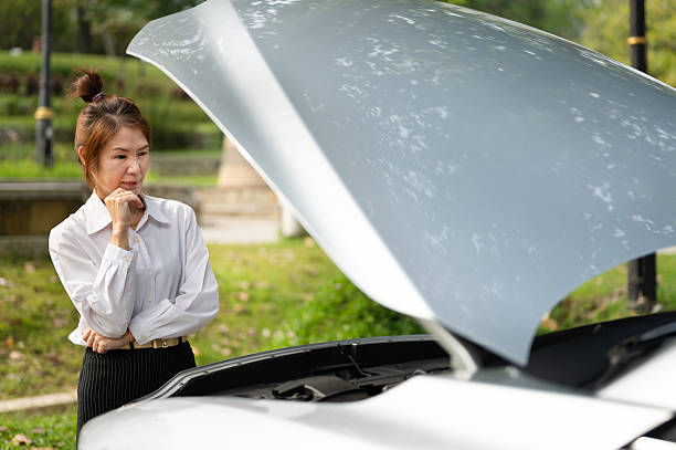 istock An Asian woman examining her broken car with open hood 2247321367