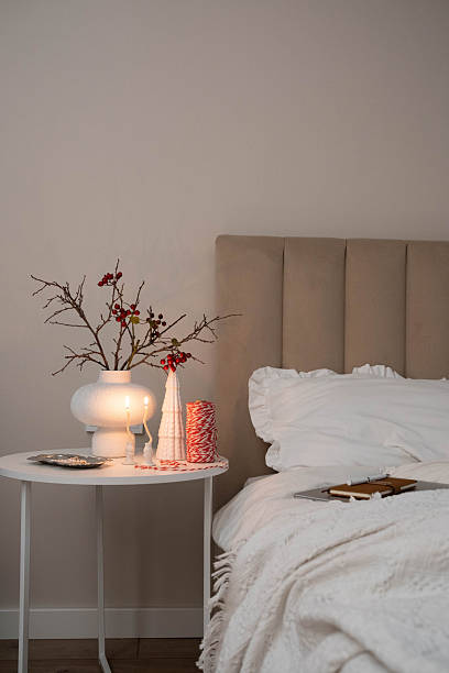 istock Cozy Christmas decor in a light and bright bedroom, bed, white bed sheets, fir branches in a white vase, candles on white table 2247321400