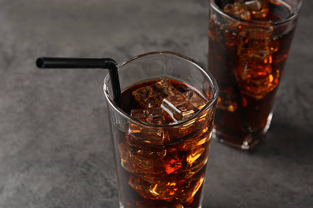 istock Cold cola with ice cubes in glasses on grey table, closeup 2247322050