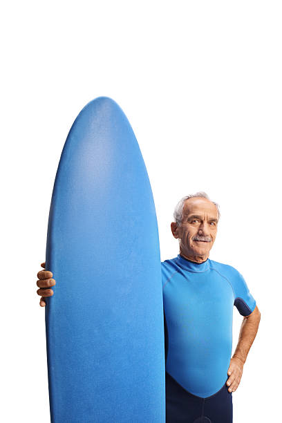istock Elderly man in a wetsuit with a surfing board 2247324121