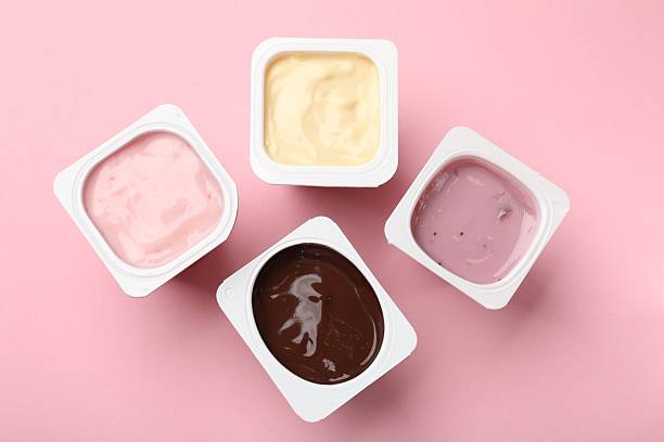 istock Delicious yogurts in plastic cups on pink background, flat lay 2247324284