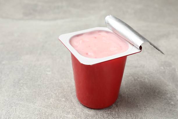istock Delicious yogurt in plastic cup on gray textured table, closeup. Space for text 2247324315