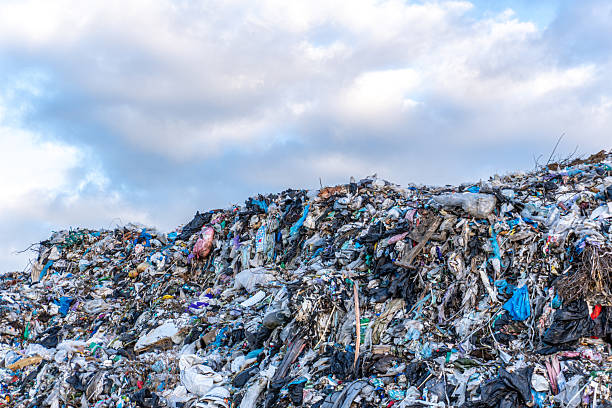 istock Landfill site filled with waste materials under cloudy sky in an urban area 2247326649