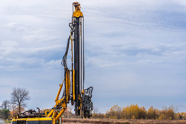 istock Construction equipment drills in a field under a cloudy sky during autumn 2247326664