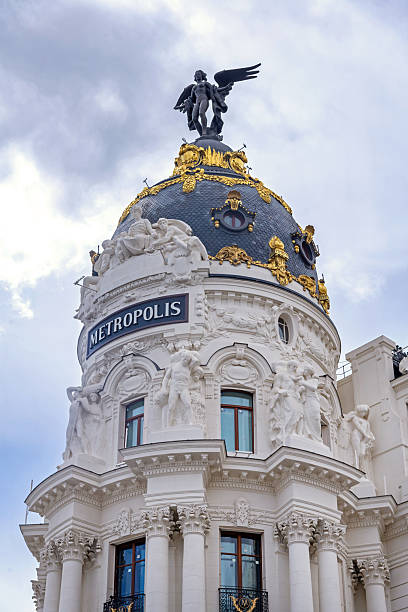 The Metropolis Building in Madrid stands at Gran Vía’s entrance, its elegant white facade and famous black dome topped with a statue rising above the busy avenue