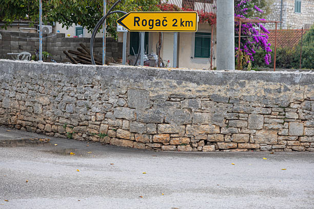 istock Rogac Road Sign Amid Lush Greenery and Stone Wall Backdrop, Solta, Croatia 2247329359