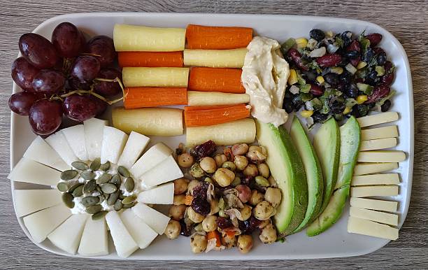 Delicious fresh food, including purple grapes, white melon, yogurt, pumpkin seeds, garbanzo salad, avocado, white cheddar, black bean salad, hummus, carrots