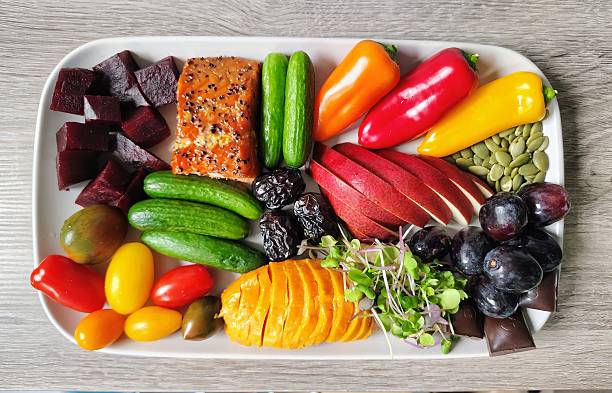Delicious fresh food, including beets, cherry tomatoes, mini cucumbers, smoked salmon, sweet peppers, apple, Ajwa dates, dark chocolate, pumpkin seeds, microgreens over hummus, purple grapes