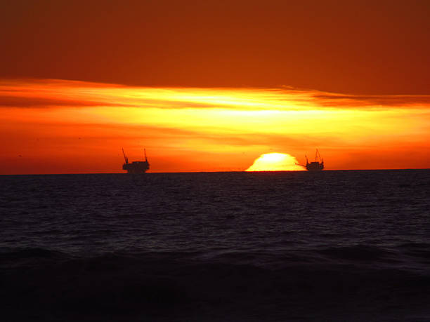 Sunset beach with a surfer on the board, and a cargo boat at the horizon