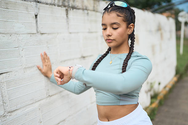 istock Young woman checking fitness tracker while stretching outdoors 2247336900