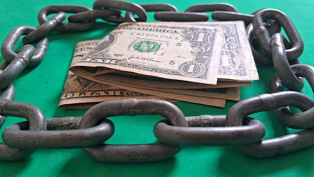 istock Dollar bills surrounded by a steel chain 2247338098