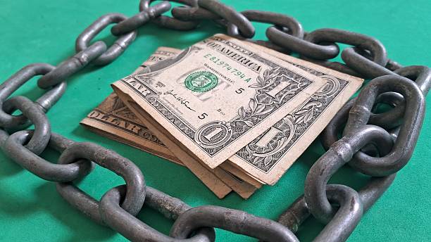 istock Dollar bills surrounded by a steel chain 2247339285