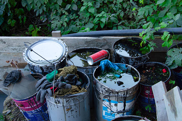 istock Several rusty paint cans overflow with dirty water and debris in a messy outdoor space surrounded by dense plants and trees 2247343083