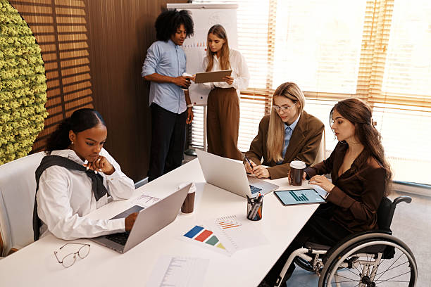 istock Inclusive team working at office table, woman in wheelchair using digital tablet 2247343971