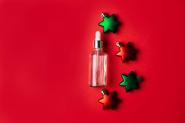 istock Cosmetic serum with star shaped Christmas ornaments on red background, copy space 2247347440