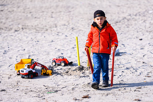 istock Boy playing construction site with toy trucks in sand 2247352378