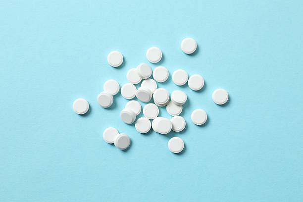istock White medicine pills on blue background. Pharmacy background 2247352653