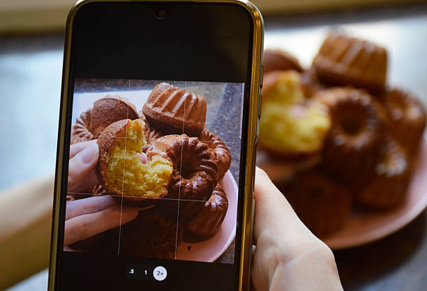 istock Women's hands holding a smartphone and photographing cupcakes 2247353794