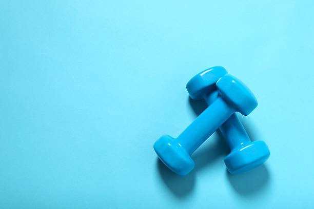 istock Fitness concept with two blue dumbbells on color background, closeup 2247353830