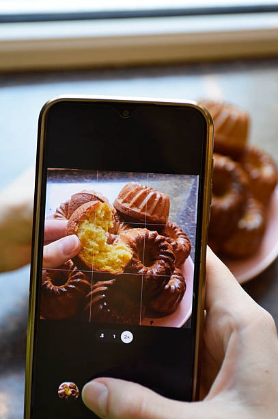 istock Women's hands holding a smartphone and photographing cupcakes 2247353869