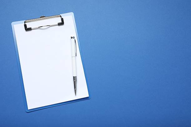 istock Clipboard with white sheet and pen on a colored background. View from above. space for text 2247353909