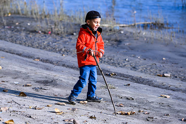Portrait of a cute Caucasian boy with blond hair, and in red jacket, on the wooden patio at a cottage house