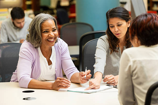 istock Three diverse women engage in a collaborative meeting, smiling and discussing ideas around a table. 2247357317