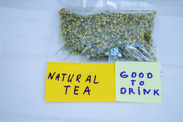 Camomile herbal tea with flower head on wooden dark desk