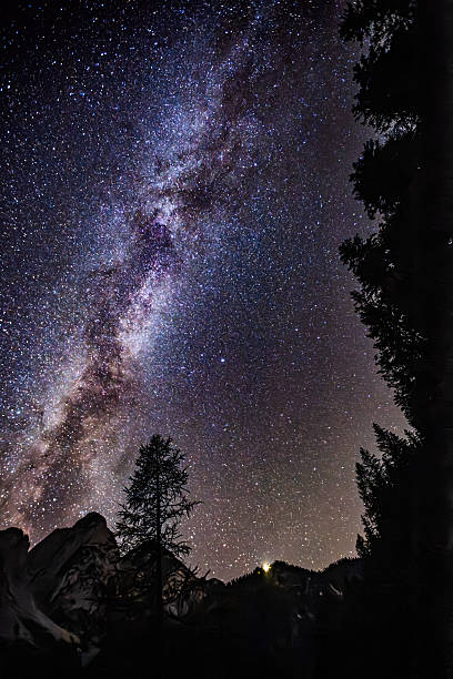 Starry night sky with glowing Milky Way arching over the rugged snow-covered Dachstein peaks in Austria