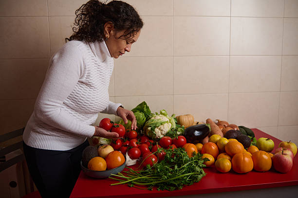 Woman Arranging Fresh Vegetables and Fruits on Red Table for Healthy Grocery Spread