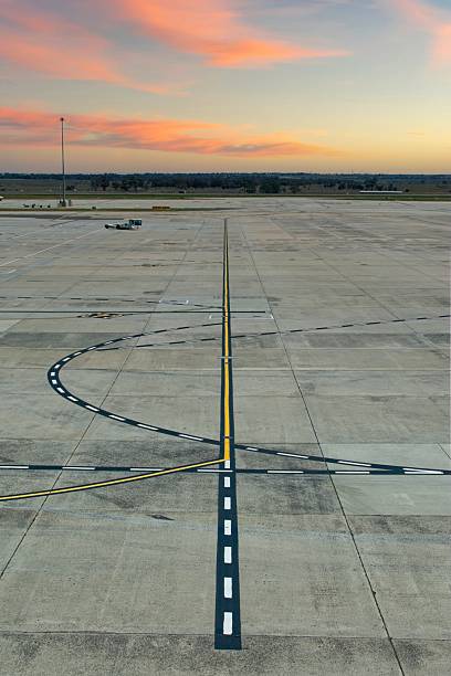 Airport runway tarmac at dawn with takeoff line markings; illustrating the concept of new beginnings, optimism, plane flight and travel.