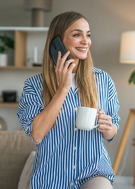 istock Woman talking on phone smiling and drinking coffee at home 2247366112